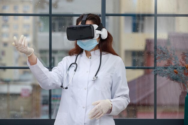 Молодая женщина-врач в очках виртуальной реальности и держит руку вверх Фото высокого качества