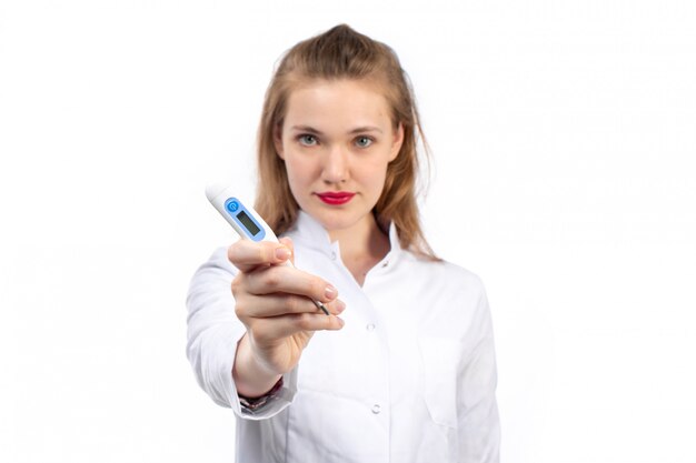 young female doctor in white medical suit holding temperature measure on the white