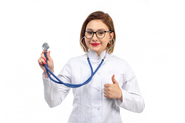 Молодая женщина-врач в белом медицинском костюме со стетоскопом слушает, улыбаясь на белом