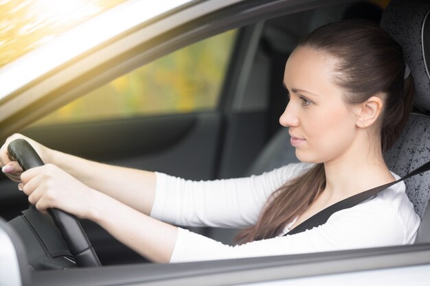 Young female driver looking at the side view mirrors