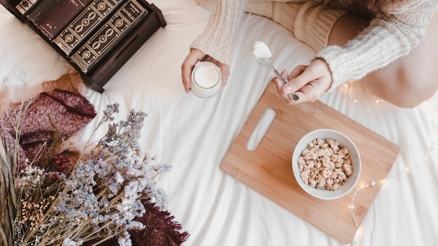 Young female enjoying yogurt on bed