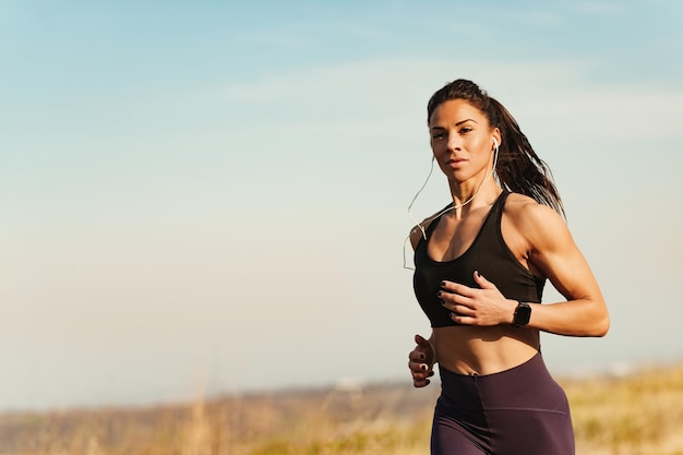 自然の中でスポーツトレーニングをしながら走っている若い女性のフィットネスインストラクターコピースペース