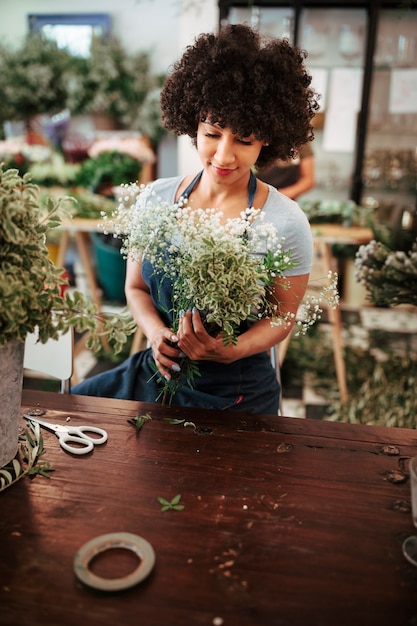 Free photo young female florist looking at bunch of beautiful white flowers