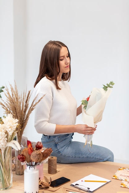 Young female florist sitting sideways with flowers