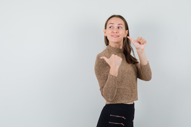 Young female in golden blouse looking back while showing thumb up and looking glad . space for text