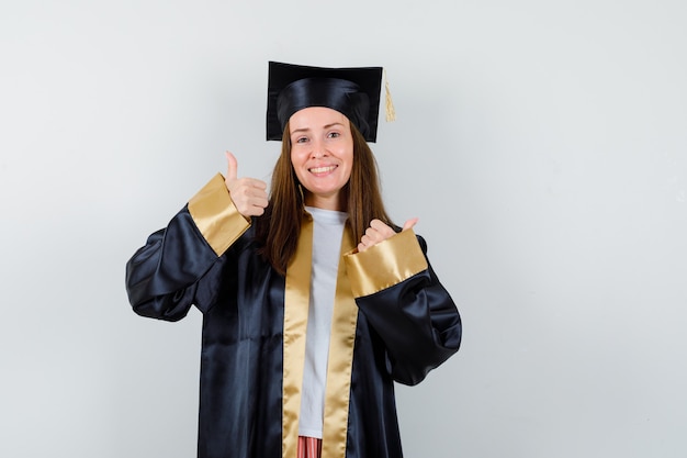 若い女性の卒業生は、アカデミックドレスを着て、幸運な顔をして、正面図を見せています。