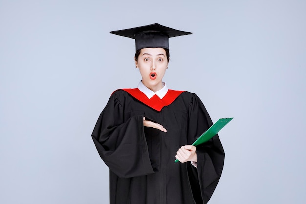 Young female graduate student pointing at diploma. High quality photo