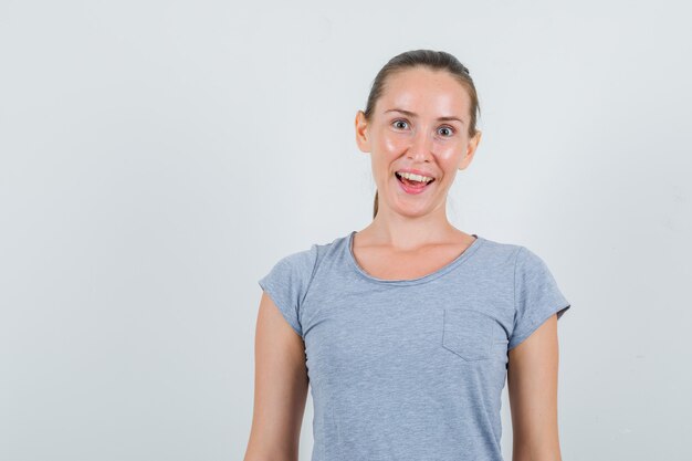 Молодая женщина в серой футболке и выглядит веселой, вид спереди.
