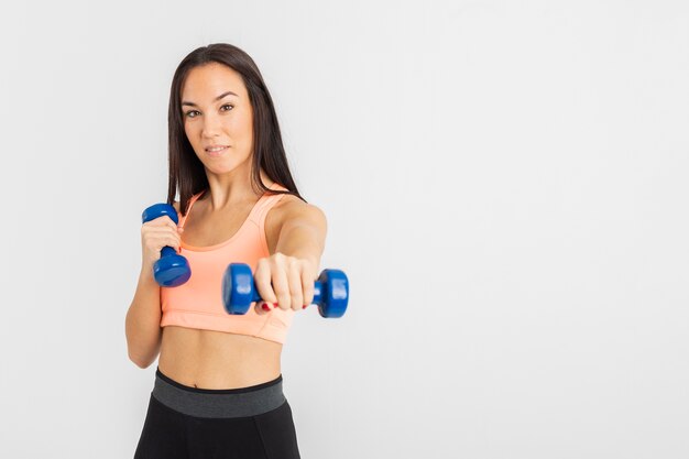 Young female at gym exercise with weights