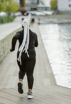 Giovane femmina divertirsi formazione all'aperto. concetto di stile di vita delle persone sportive. donna in abbigliamento sportivo jogging