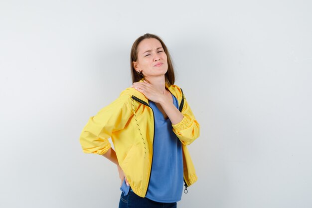 Young female having shoulder pain in t-shirt and looking tired, front view.