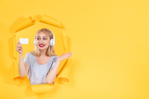 Young female in headphones with credit card on a yellow background ultrasound audio music