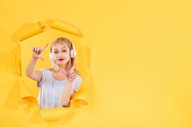 Young female in headphones on yellow background sound ultrasound music audio