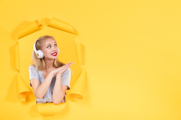 黄色い机の上のヘッドフォンの若い女性は超音波音楽オーディオを鳴らします