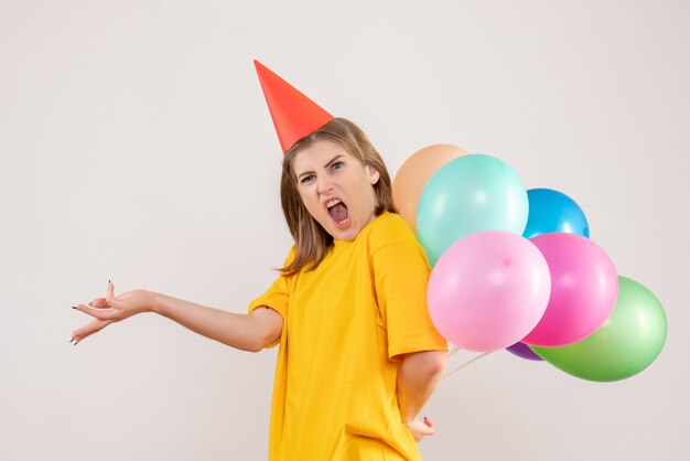 young female hiding colorful balloons behind her back on white