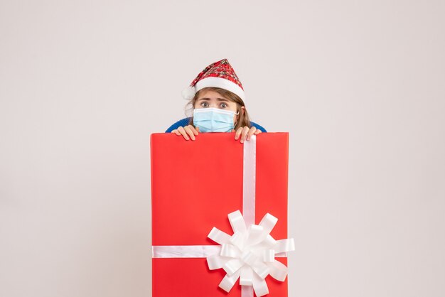 Free photo young female hiding inside present box in mask on white