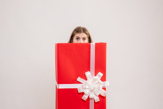 Young female hiding inside present box on white