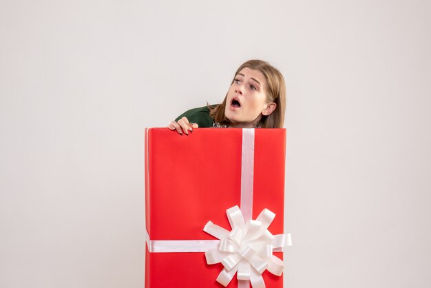 young female hiding inside present box on white