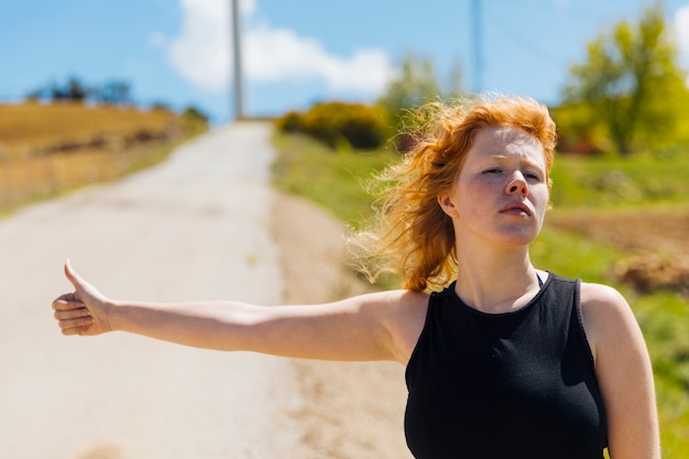 Young female hitchhiking on roadside