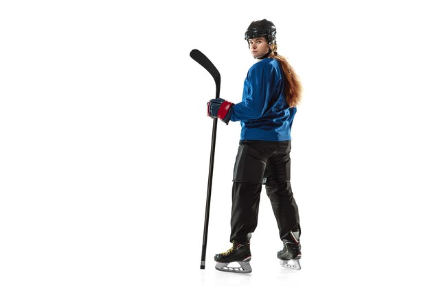 Young female hockey player with the stick on ice court and white background