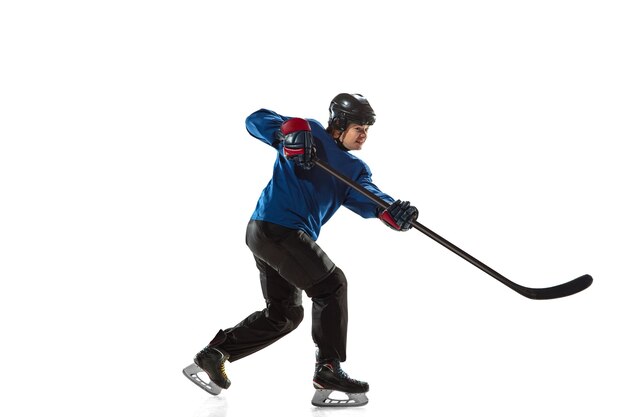 Young female hockey player with the stick on ice court and white wall