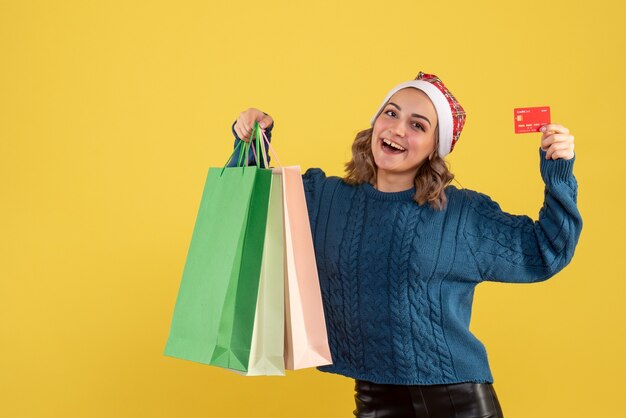 young female holding bank card and packages after shopping on yellow