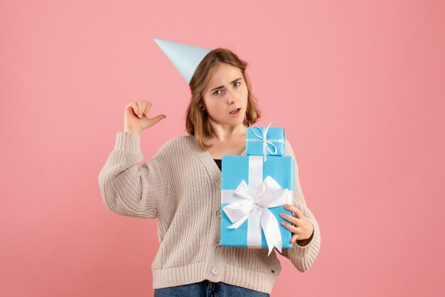 Young female holding christmas presents on pink