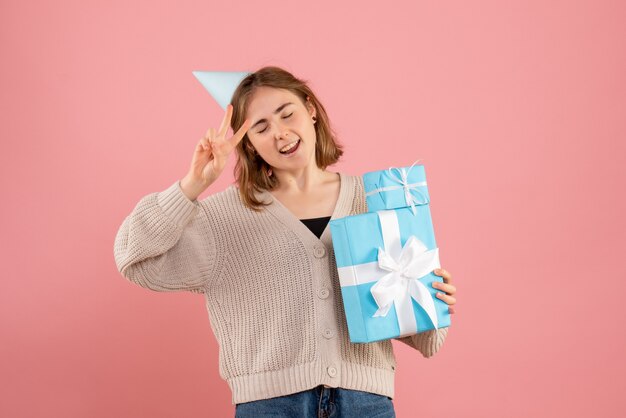 ピンクのクリスマスプレゼントを保持している若い女性