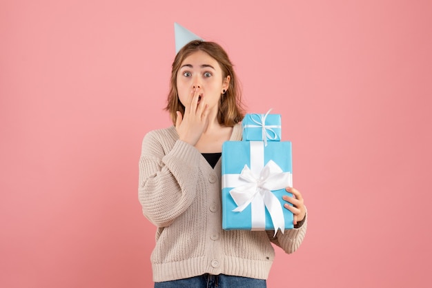 young female holding christmas presents on pink