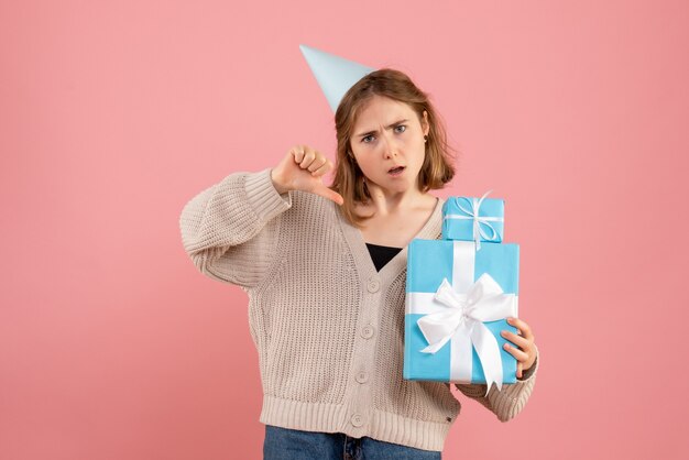молодая женщина держит рождественские подарки на розовом