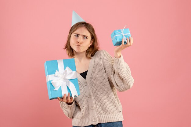 ピンクのクリスマスプレゼントを保持している若い女性