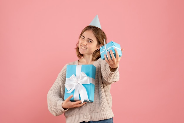 Free photo young female holding christmas presents on pink