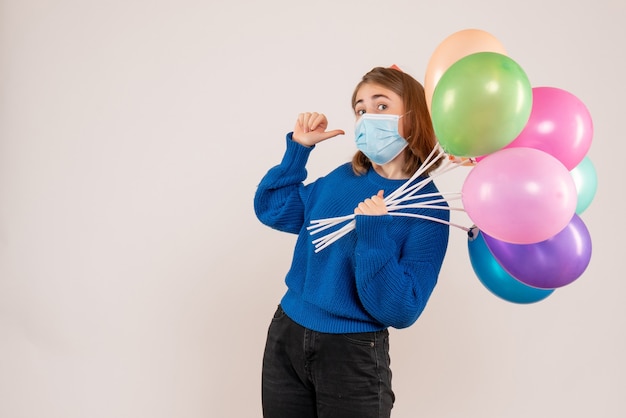 Giovane donna in possesso di palloncini colorati in maschera su bianco