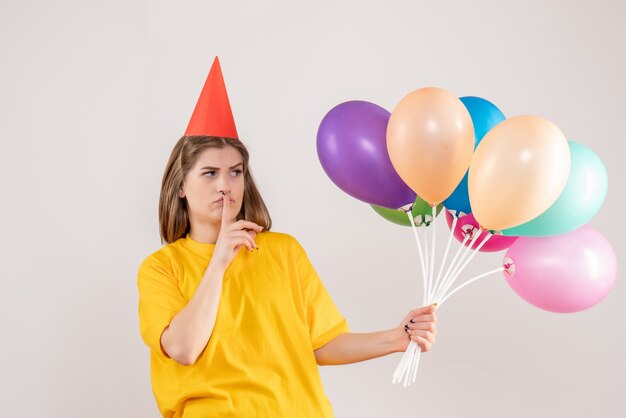 young female holding colorful balloons on white