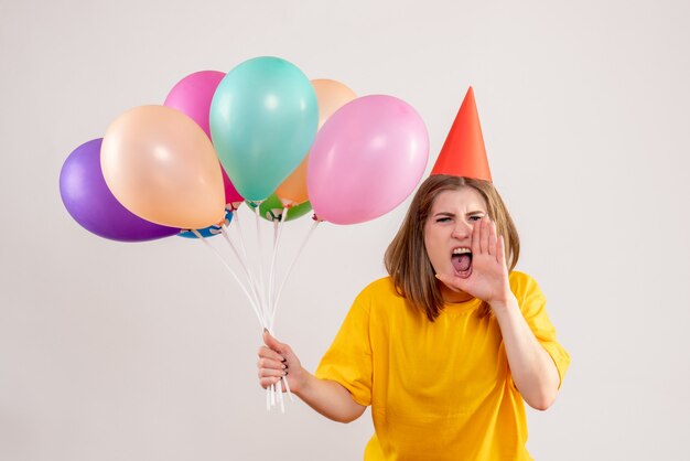 young female holding colorful balloons on white
