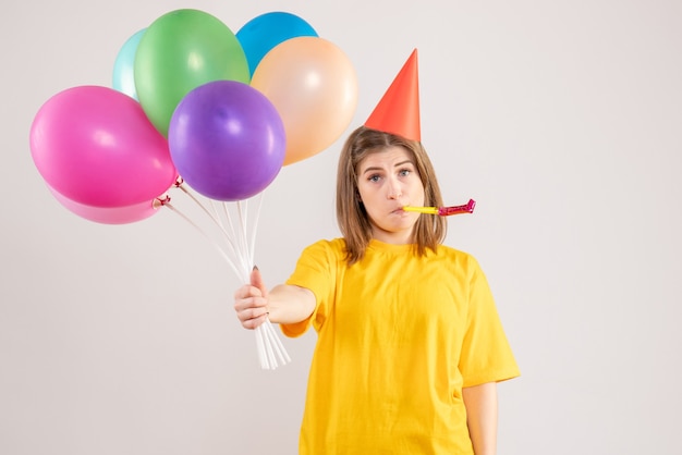 young female holding colorful balloons on white