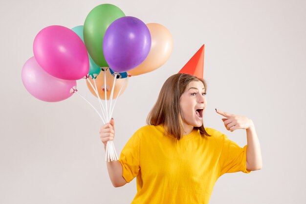 young female holding colorful balloons on white