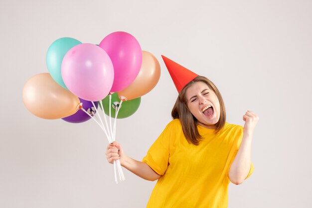 young female holding colorful balloons on white