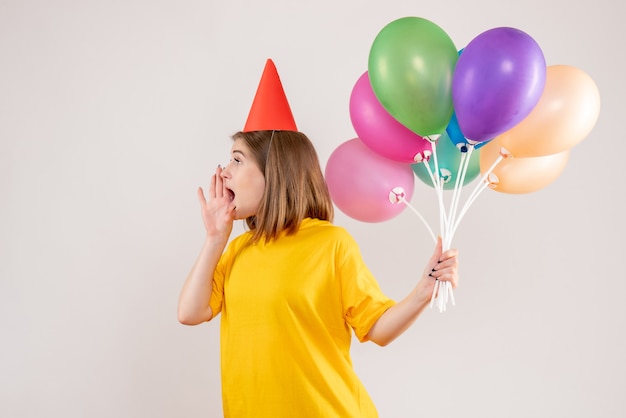 young female holding colorful balloons on white