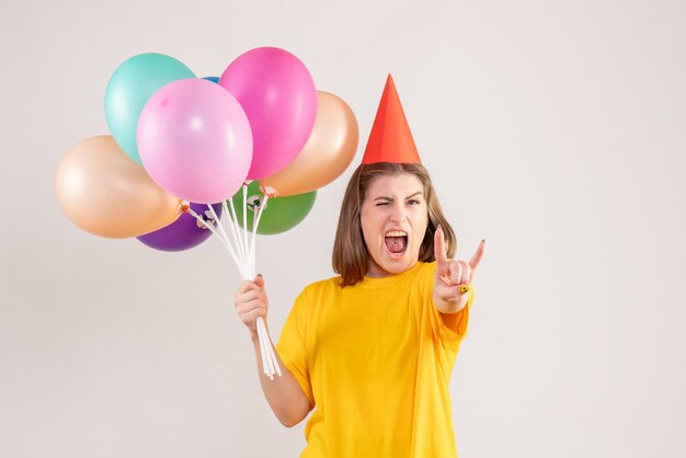 young female holding colorful balloons on white