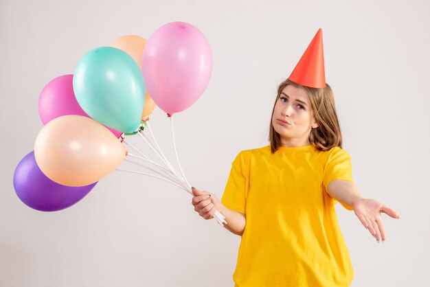 young female holding colorful balloons on white