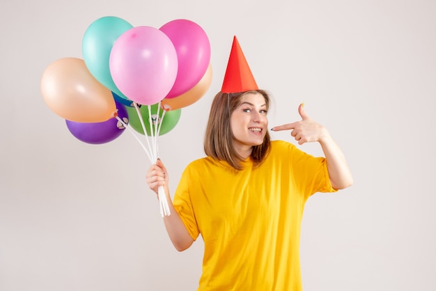 young female holding colorful balloons on white