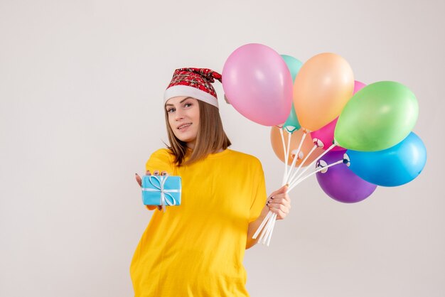 young female holding little present and colorful balloons on white