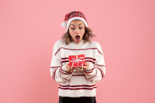 young female holding little xmas present on pink