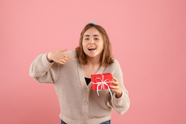 young female holding little xmas present on pink