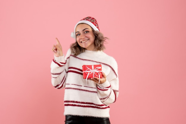 Free photo young female holding little xmas present on pink