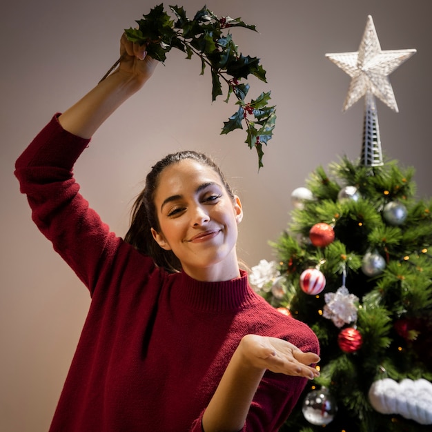 Young female holding mistletoe above head