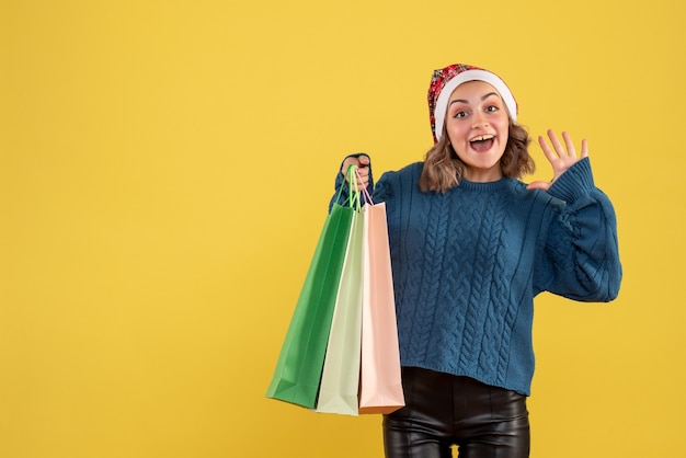 young female holding packages after shopping on yellow