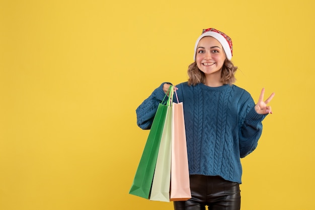 young female holding packages after shopping on yellow