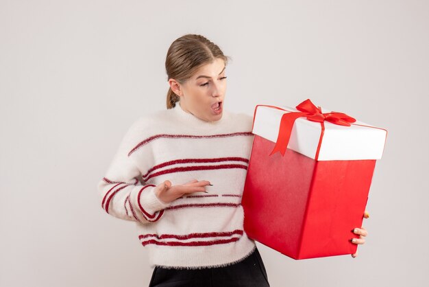 молодая женщина держит подарок в коробке на белом